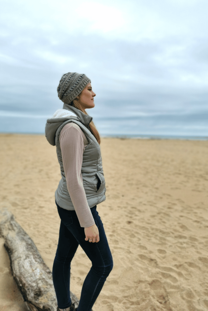 woman standing next to ocean wearing a crochet beanie hat